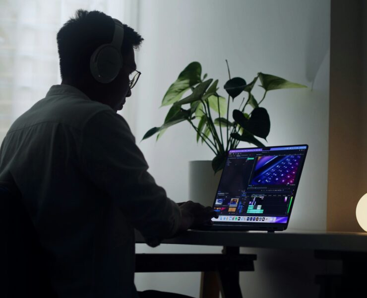 Hombre sentado frente a su computadora portátil editando una película.