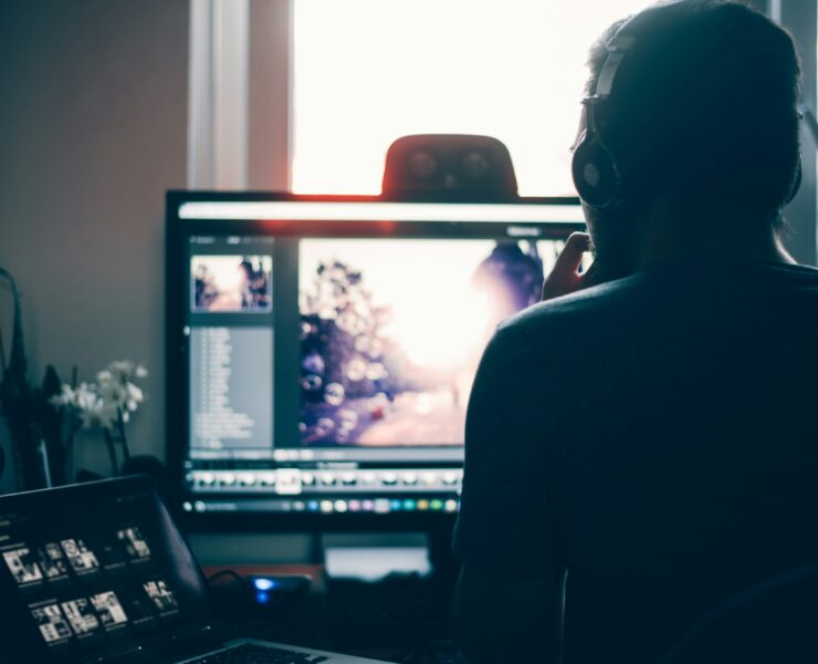 Um homem sentado em frente à tela do computador editando seu vídeo.