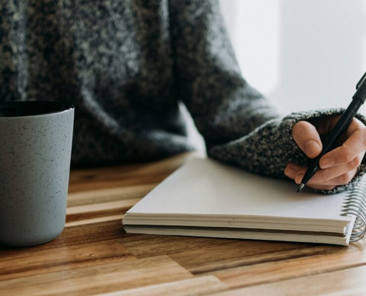 Uma mulher sentada em uma mesa, escrevendo anotações em um papel.