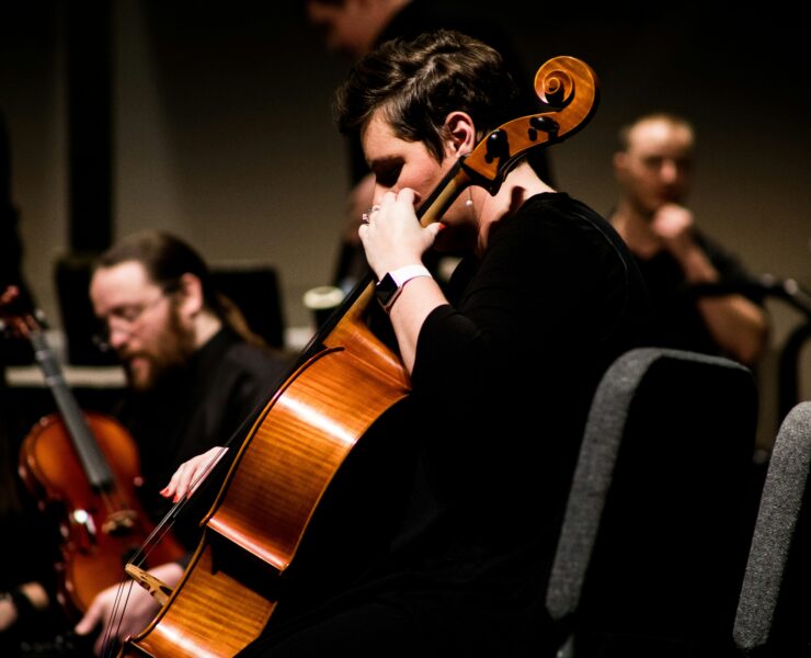 Um violoncelista tocando em uma orquestra.