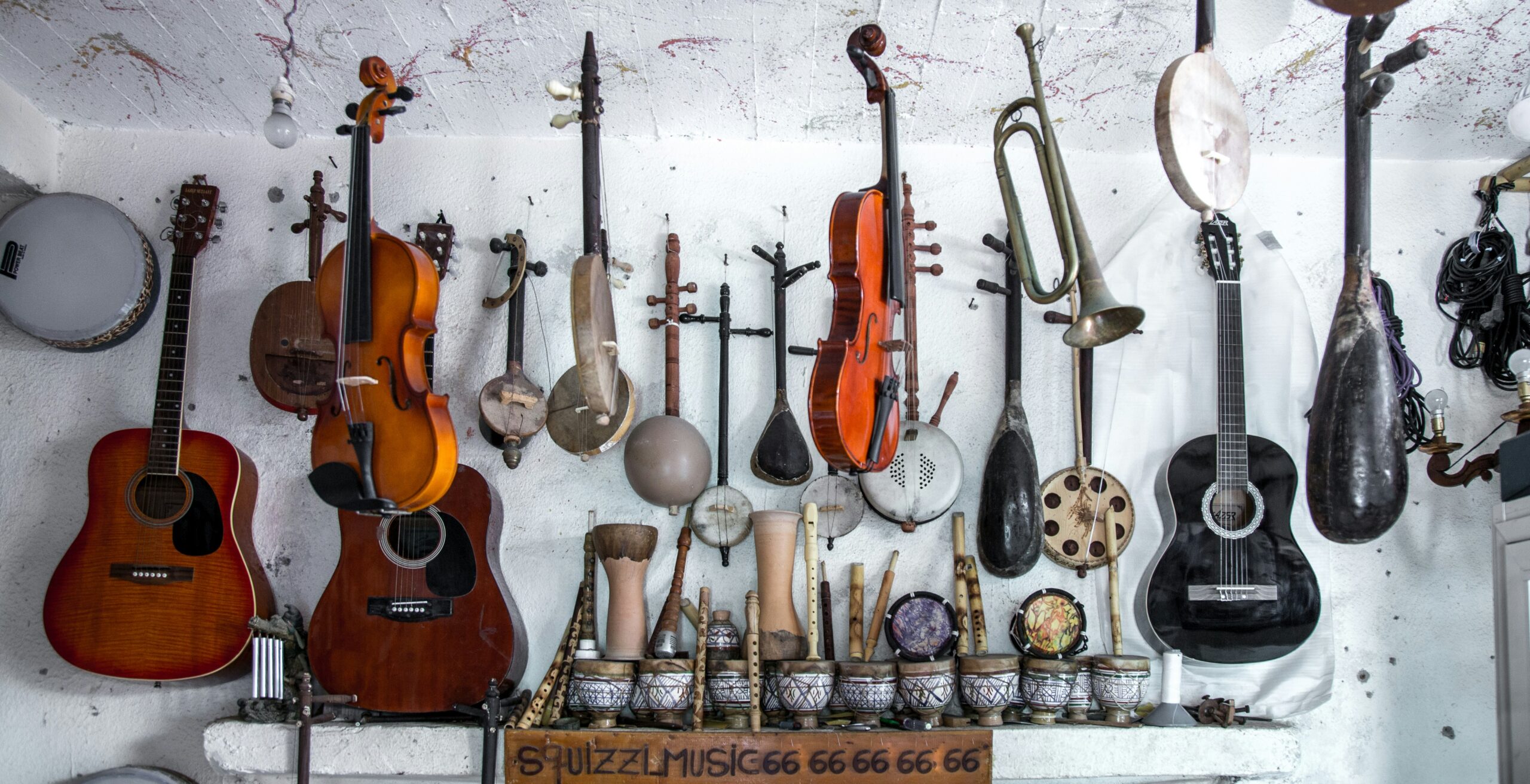 Several instruments are hanging on a white wall.