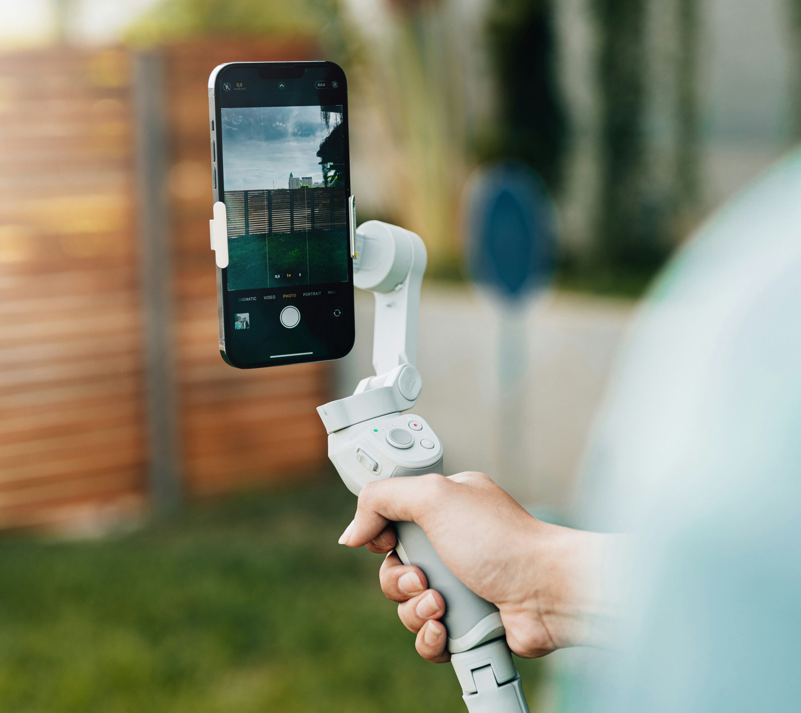 The image shows a woman holding a gimbal with her smartphone attached. A gimbal is used to stabilize shots and to keep an object stay level while its base moves or tilts.